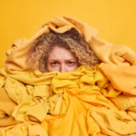 Image of woman organizing clothing - surrounded by a pile of yellow clothing